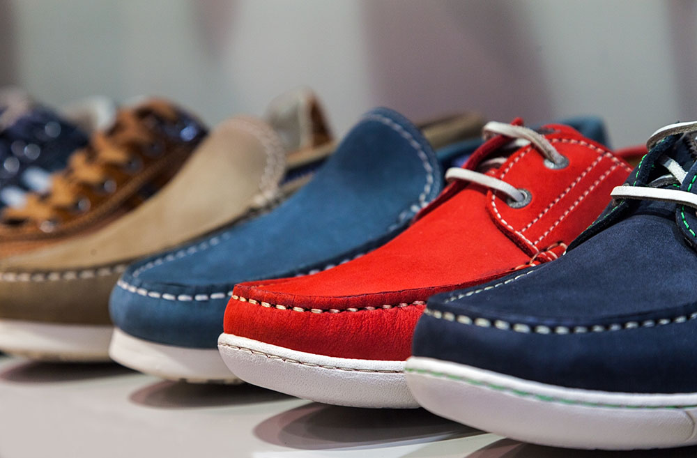 A row of colorful summer masculine shoes on a shelf of a shoes store.Selective focus on the red one.