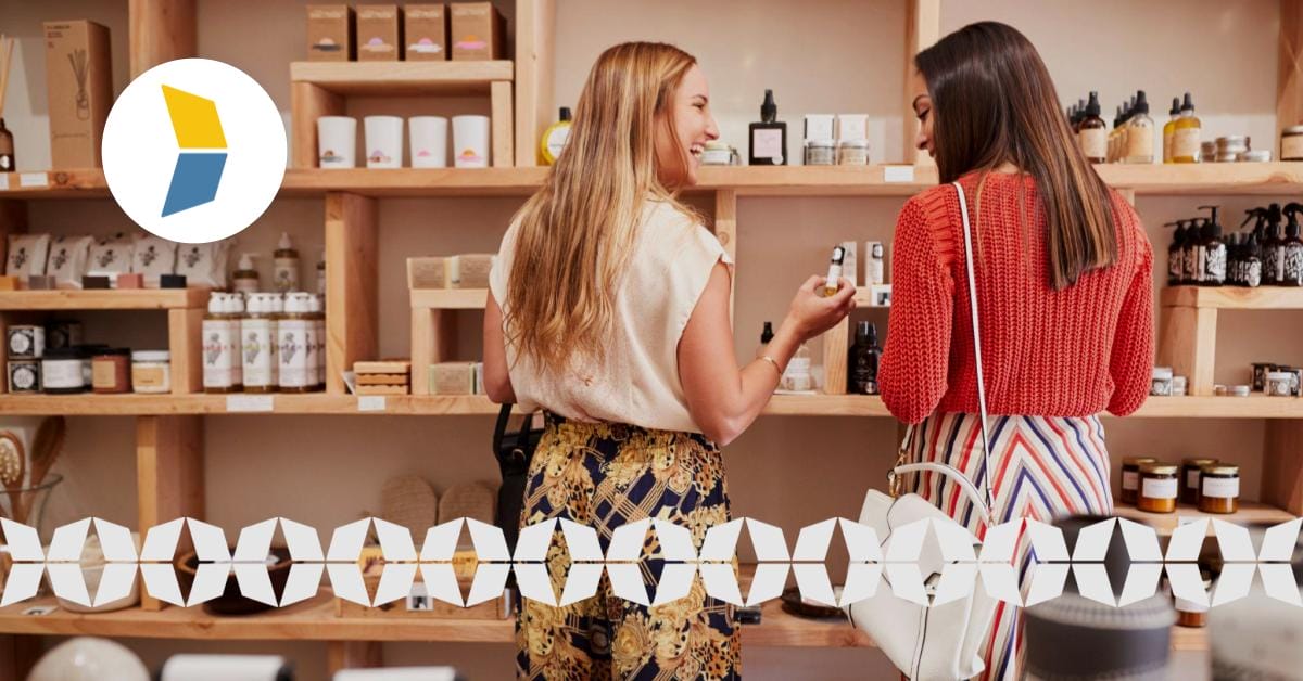 two women smiling at each other while shopping at a retail store