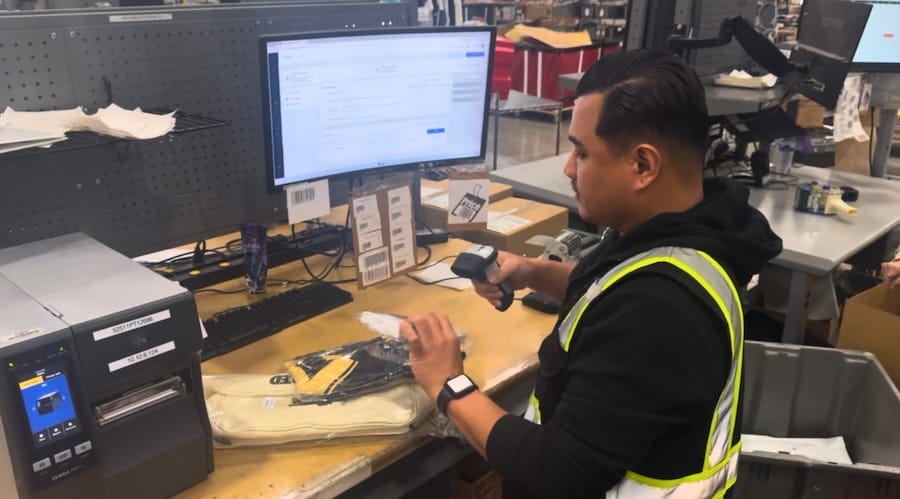 warehouse worker scanning product sku with omnichannel fulfillment dashboard on computer