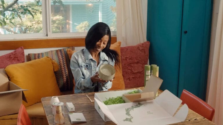 woman at home opening personalized DTC fulfillment package from Matcha green tea brand