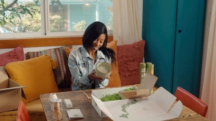 woman at home opening personalized DTC fulfillment package from Matcha green tea brand
